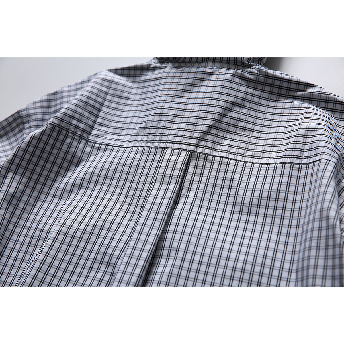 Close-up of the white-and-black checked shirt back, showing the shoulder yoke and center pleat.