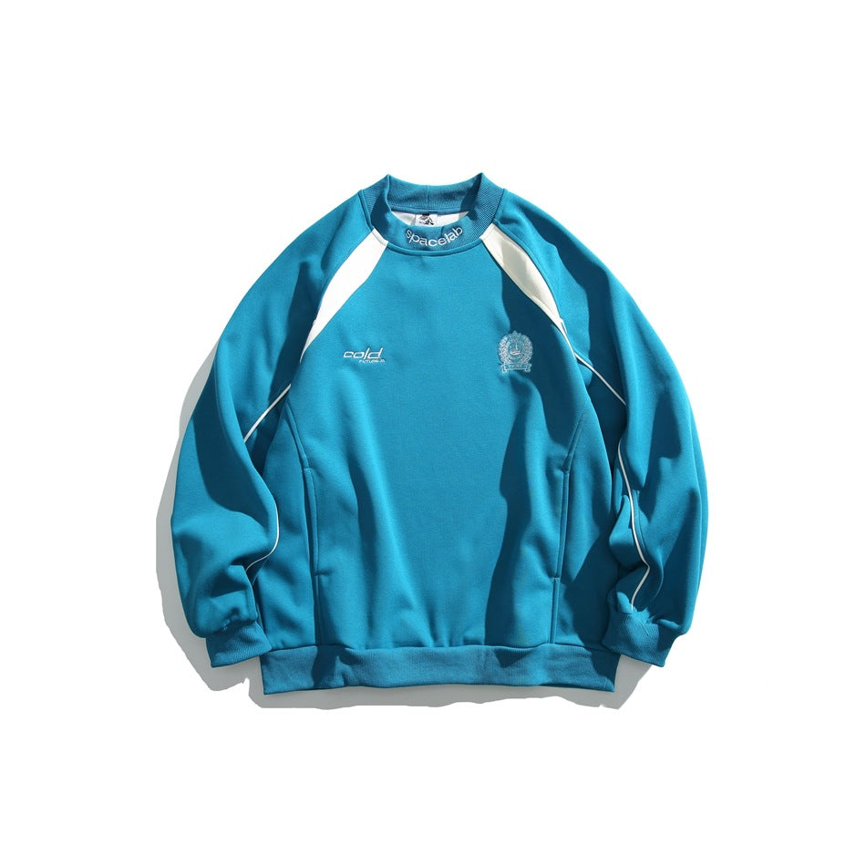 Blue crewneck sweatshirt with cream raglan shoulder panels, sleeve piping, embroidered chest crest and ribbed trims, flat lay