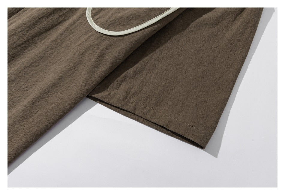 Close-up of the brown shirt's sleeve and hem, with part of the pale-trimmed pocket visible.