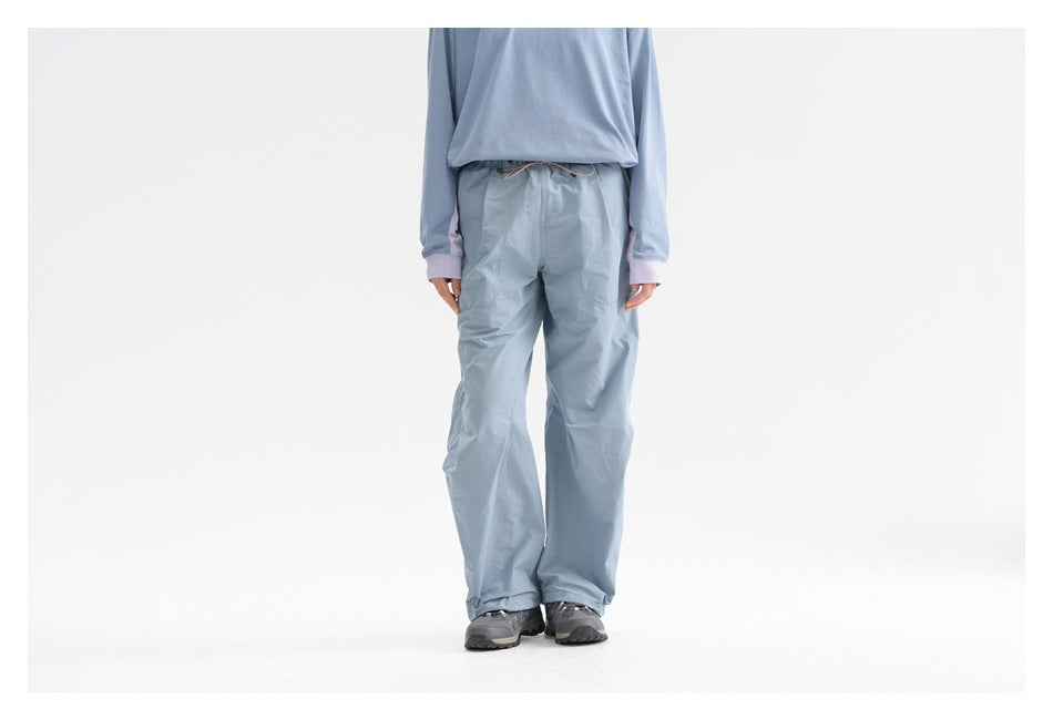 Front view of a person wearing light blue wide-leg drawstring pants with a matching blue top.