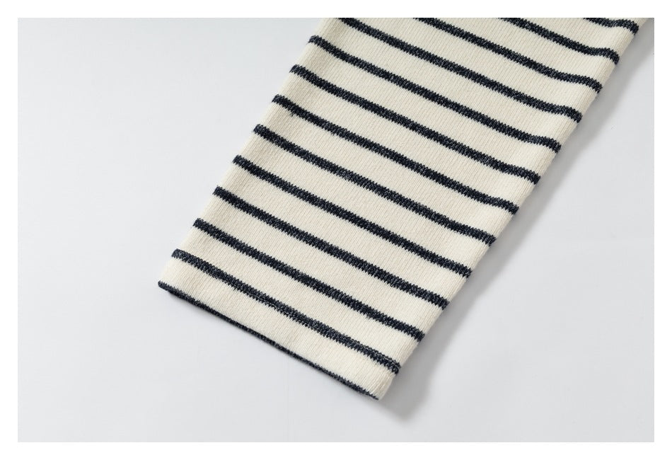 Close-up of a cream knit sleeve with narrow charcoal horizontal stripes.