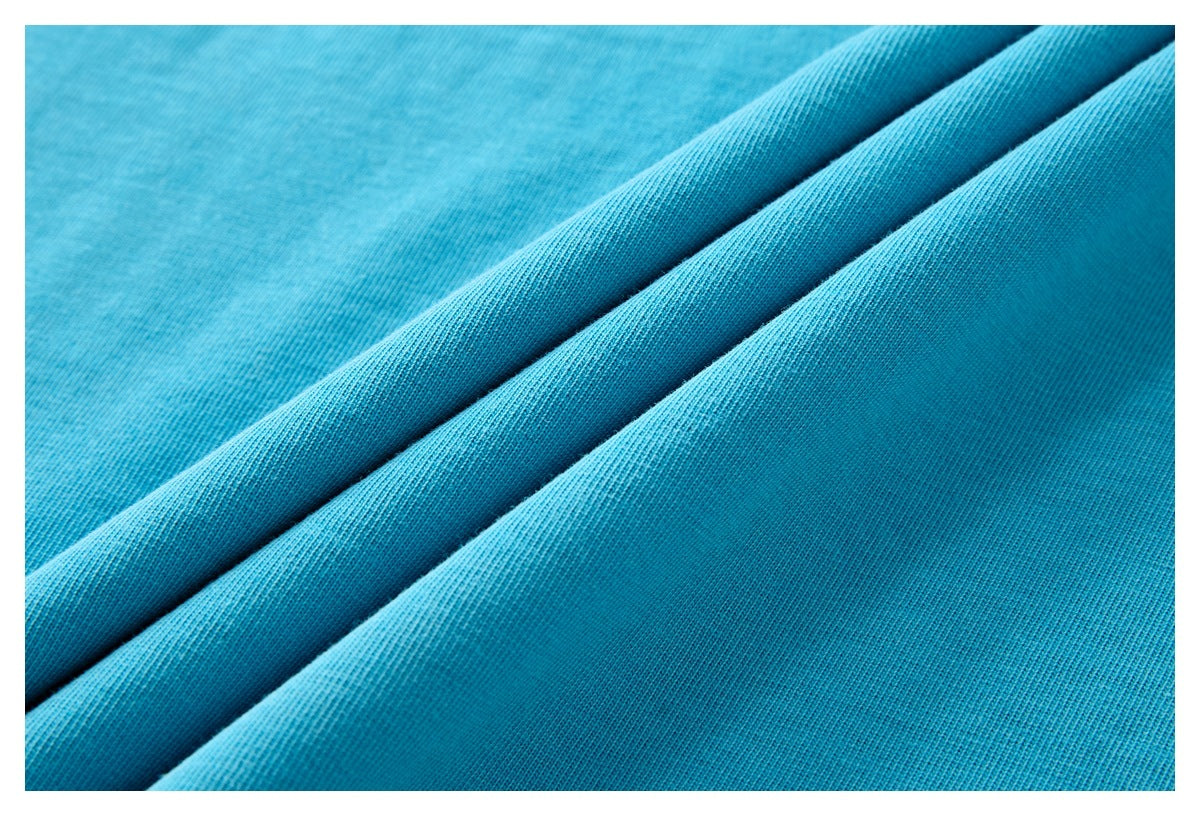Close-up of bright turquoise-blue fabric folded into soft diagonal ridges, showing a fine knit texture.