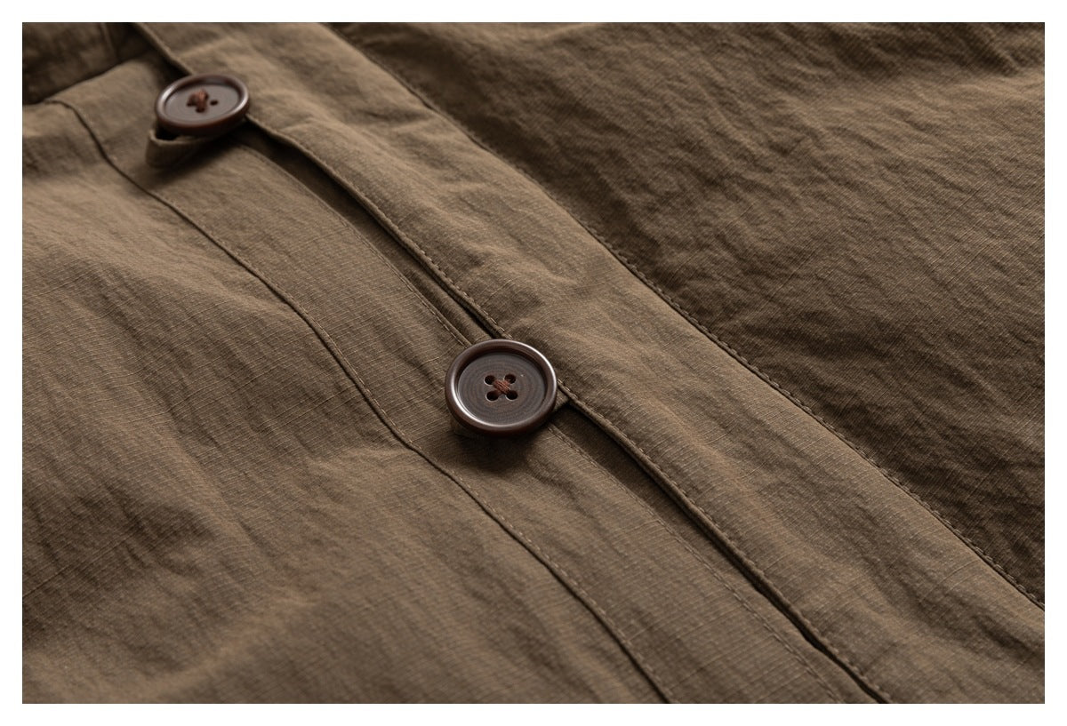 Close-up of brown jacket fabric and a button fastening on the front placket.