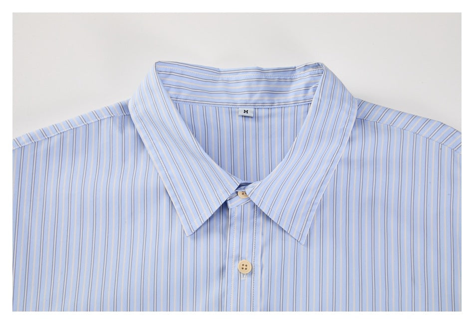 Front close-up of a light blue button-up shirt with fine vertical stripes, a pointed collar, and beige buttons.
