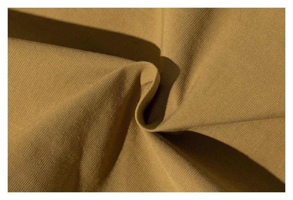Close-up of mustard-brown fabric gathered into soft folds, showing its fine surface texture.