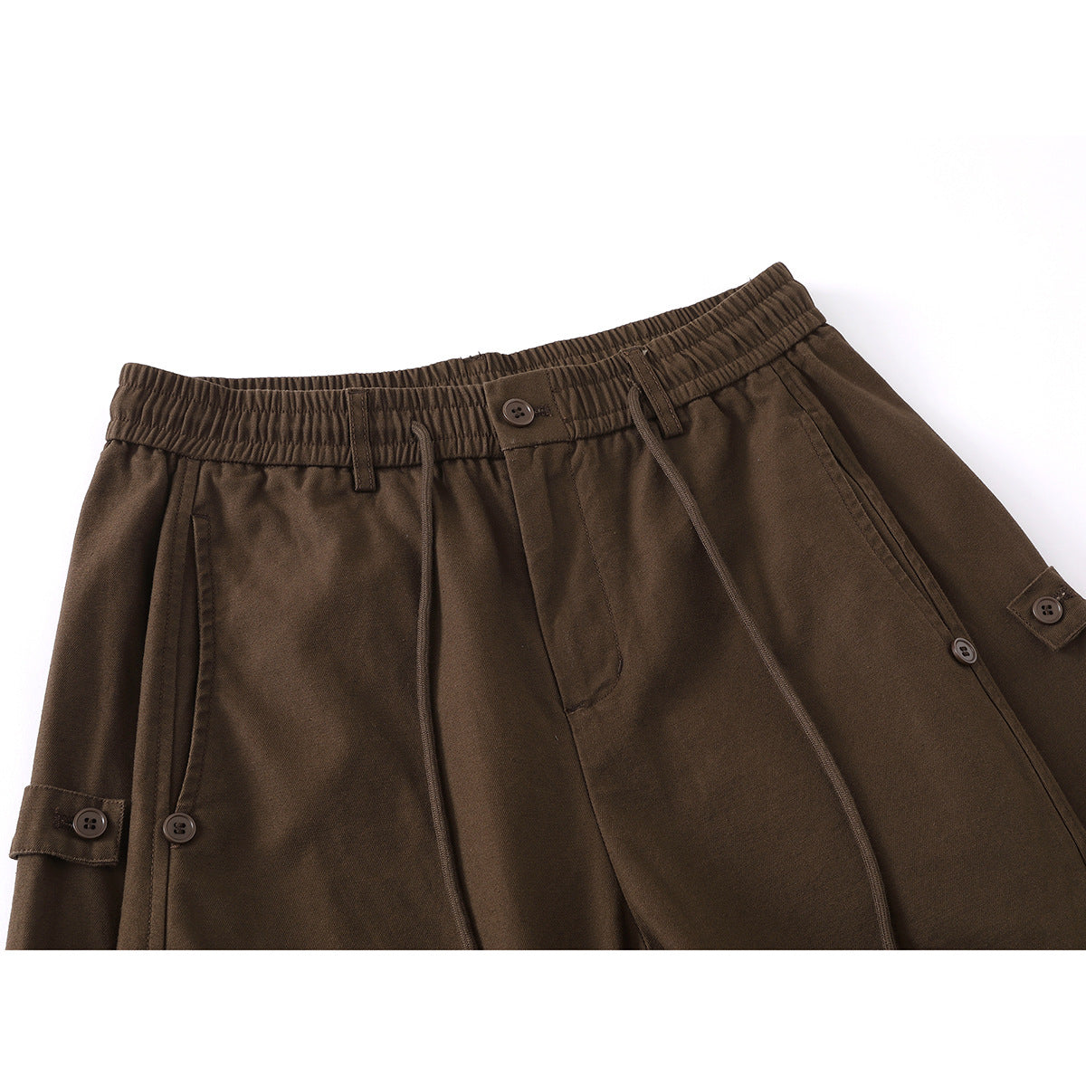 Close-up of dark brown pants showing an elastic waistband, drawstrings, button closure, and buttoned side tabs.