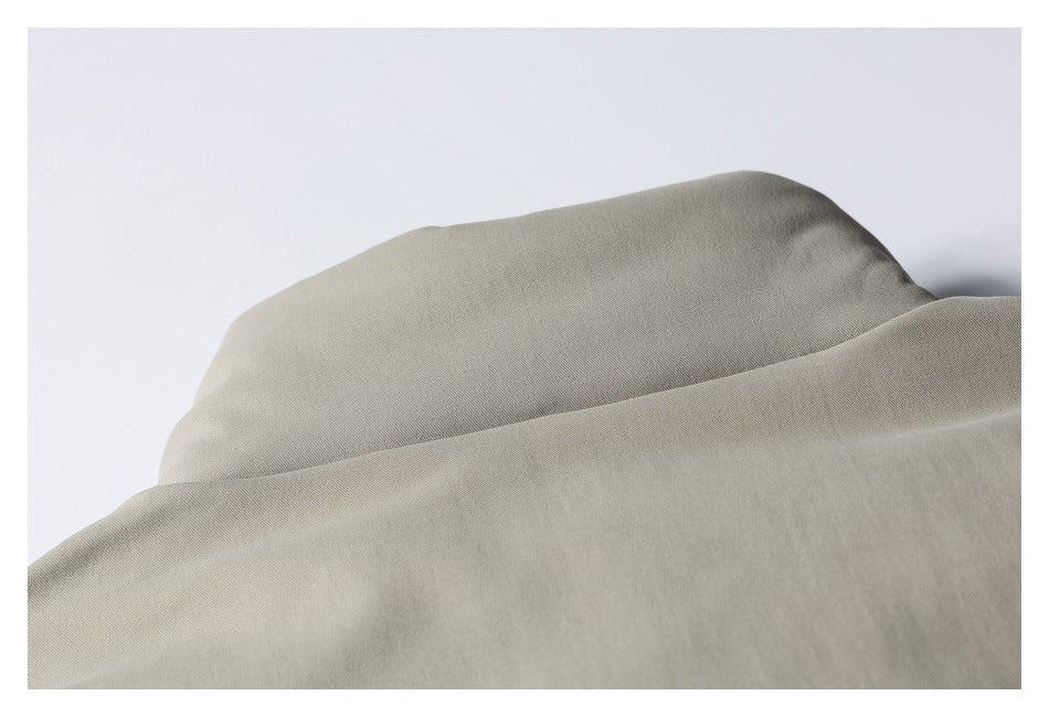 Close-up of softly draped taupe-gray garment fabric showing its fine diagonal weave.