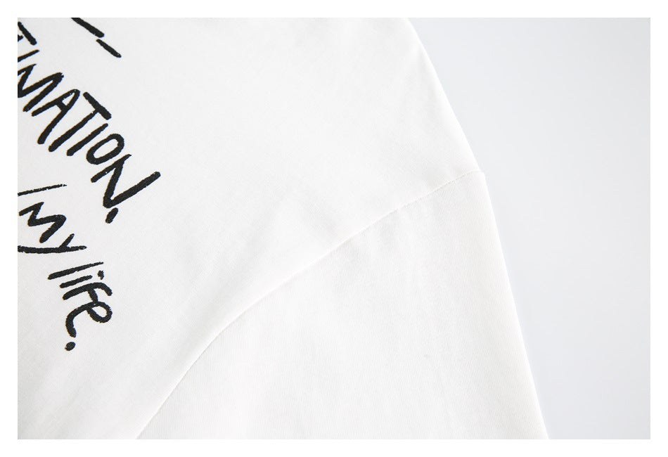 Close-up of a white garment with partial black lettering and a curved seam.