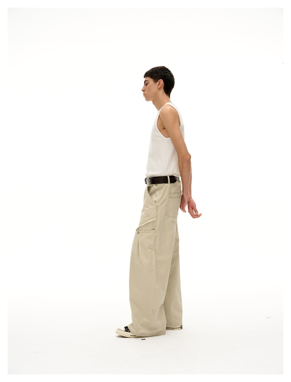 Side view of a model wearing beige wide-leg pants with a buttoned knee panel and a white tank top.