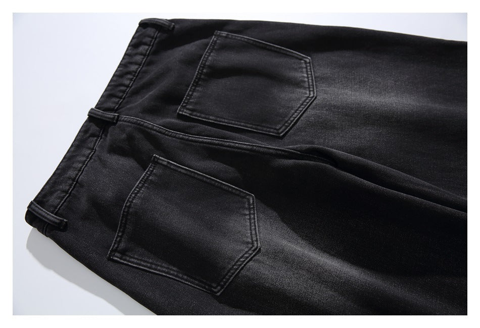 Back-pocket detail of black jeans, showing two stitched pockets and belt loops.
