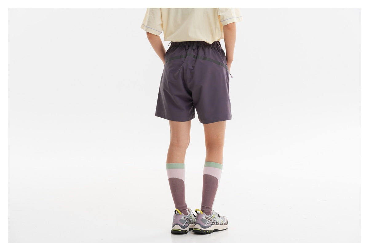 Rear view of a model wearing dark purple shorts with a reflective stripe across the back.