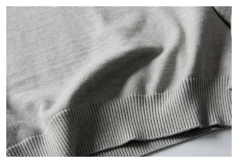 Close-up of the light gray sweater's ribbed bottom hem and knit texture.