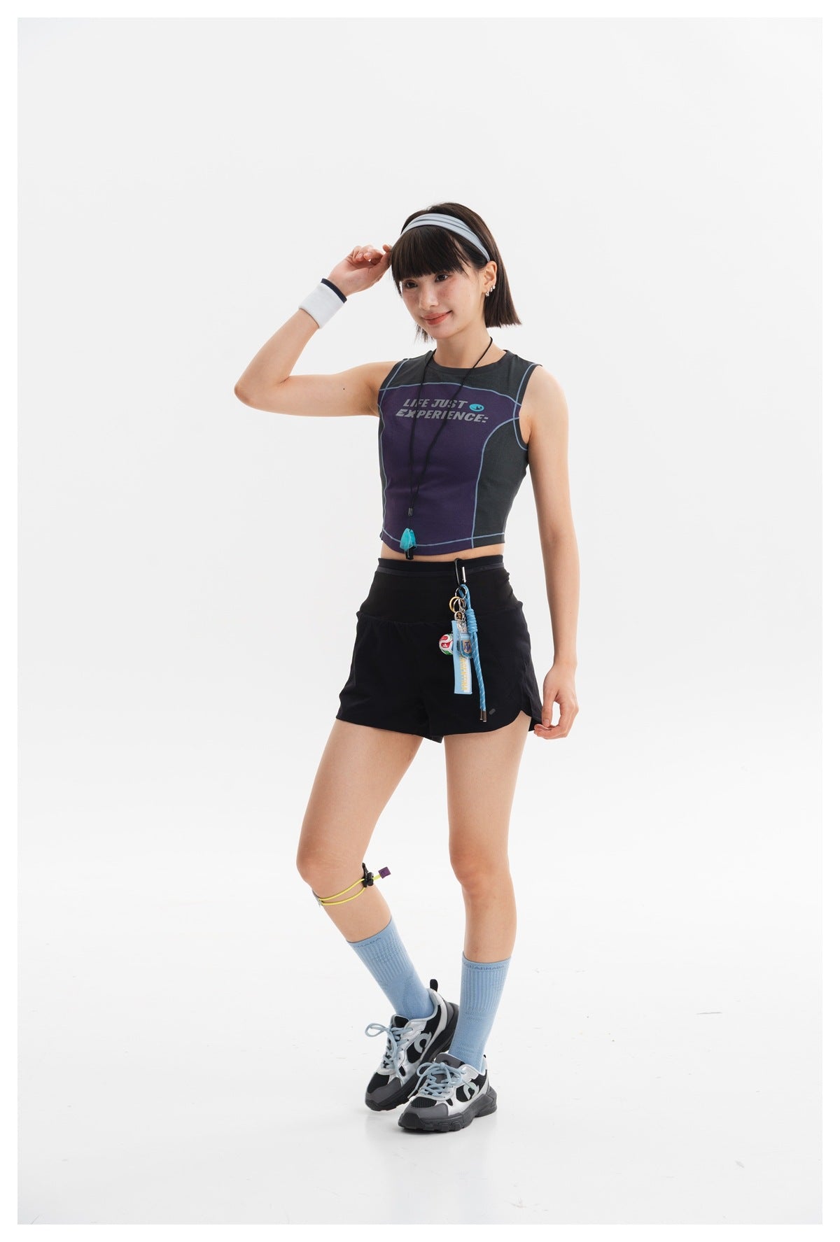 Model wearing a purple and charcoal sleeveless crop top with blue piping and black shorts.