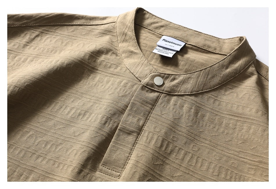 Close-up of the tan shirt's band collar, single button, short placket, and raised geometric pattern.