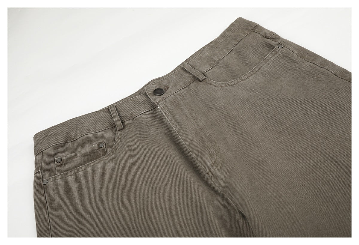 Angled close-up of taupe-gray pants showing the front waistband, button, fly, belt loops, and curved pockets.