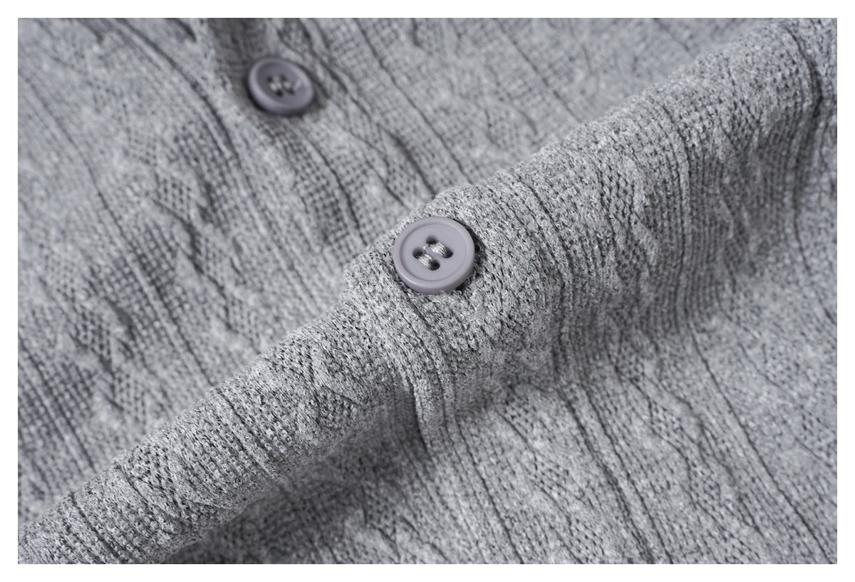Close-up of a gray knit shirt sleeve cuff and button against the patterned fabric.