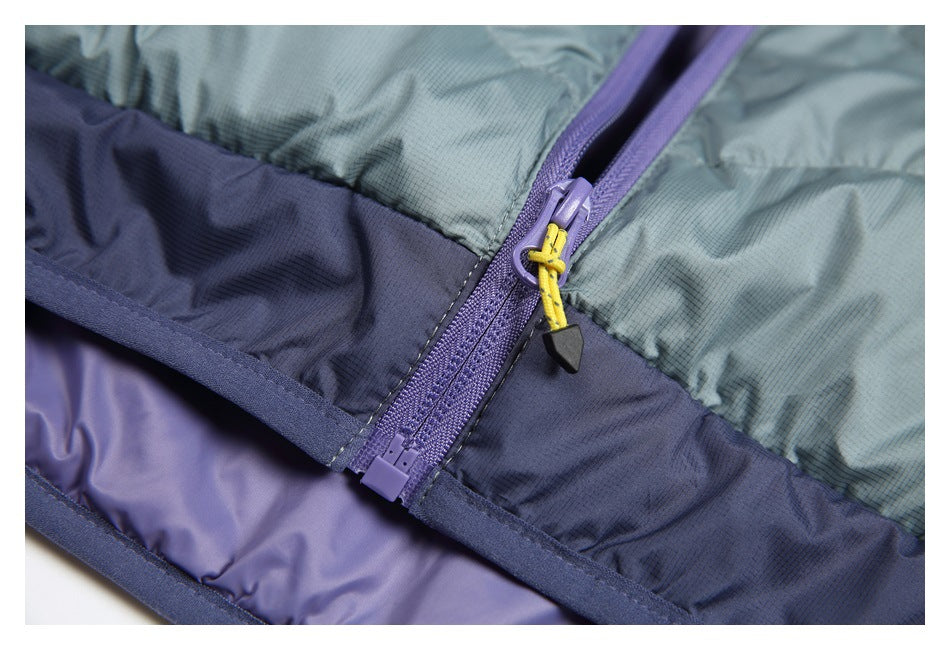 Close-up of a purple zipper with a yellow pull cord between sage-green and navy panels on a padded garment.