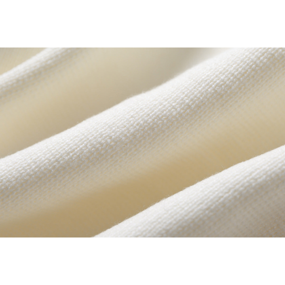 Macro view of the ivory sweater’s knit texture and raised ribbed stitching.
