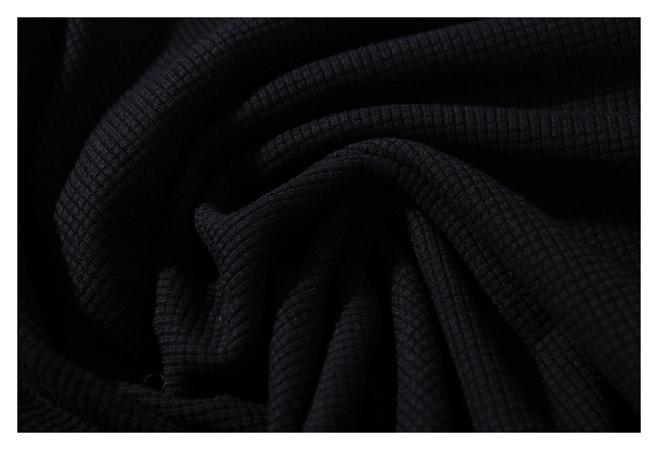 Close-up of dark black ribbed fabric gathered into soft folds.