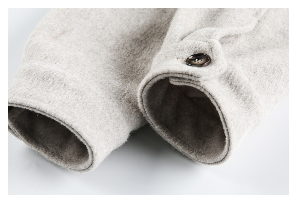 Close-up of a pale beige coat sleeve cuff with a dark button and soft, fuzzy texture.