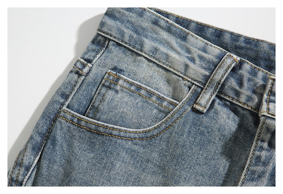 Close-up of the front pocket, coin pocket, belt loop, and contrast stitching on washed blue jeans.