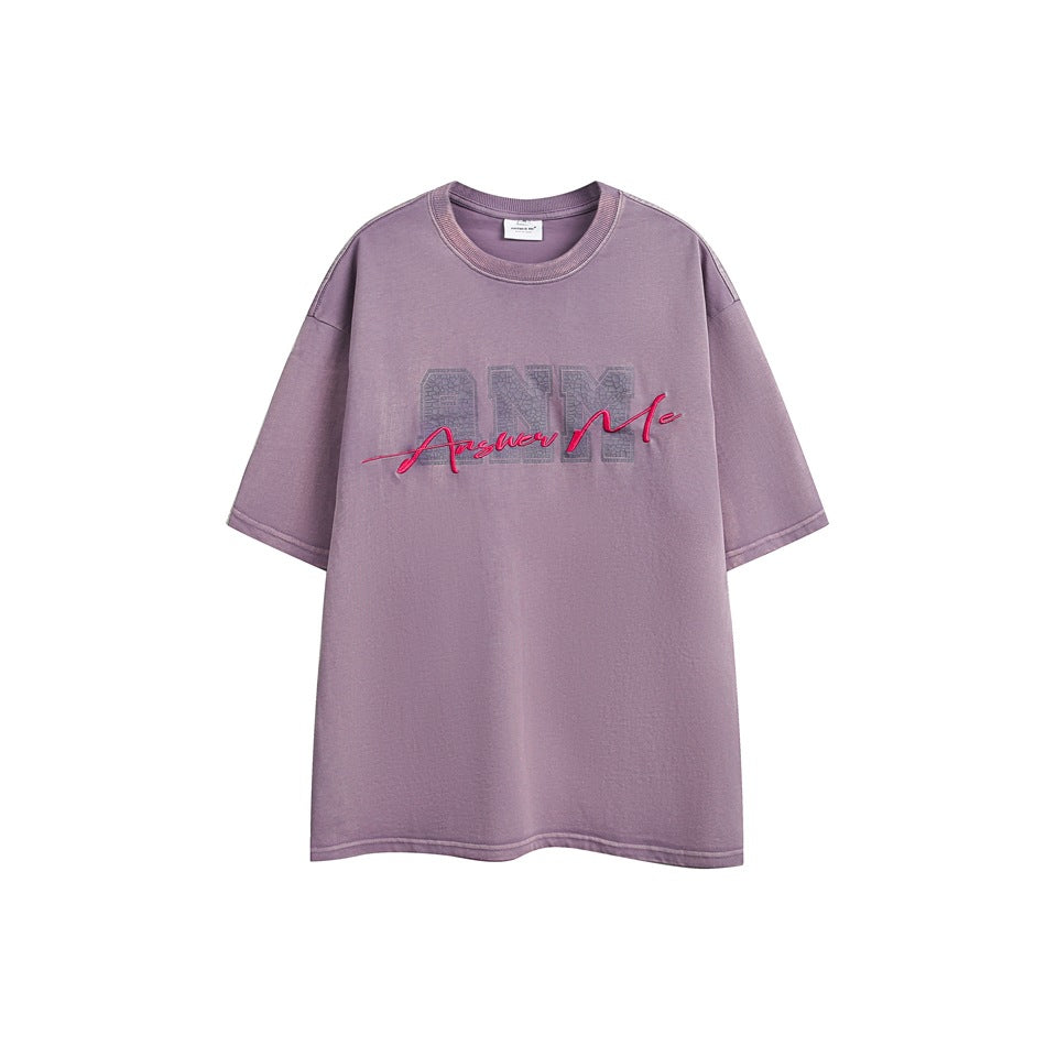 Purple short-sleeve crew-neck T-shirt with pink Answer Me script embroidery over a gray ANM patch