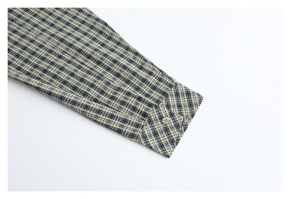 Close-up of a long sleeve and buttoned cuff on the cream and dark plaid shirt.