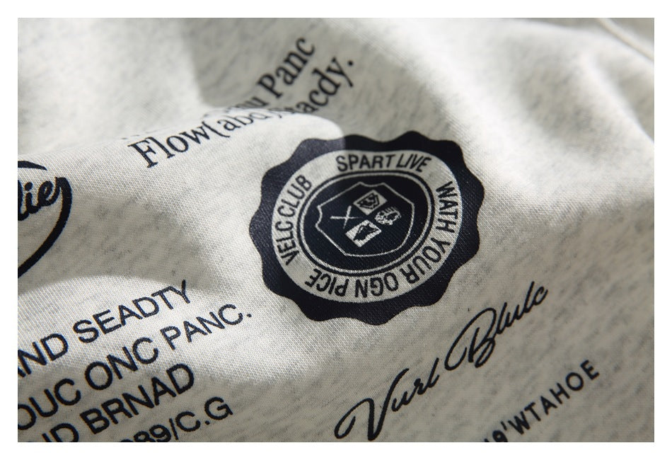 Close-up of a dark circular emblem and text printed on heathered light-gray sweatshirt fabric.