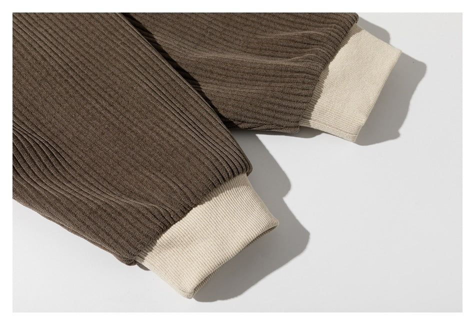 Close-up of two brown ribbed garment cuffs with contrasting cream ribbed bands.