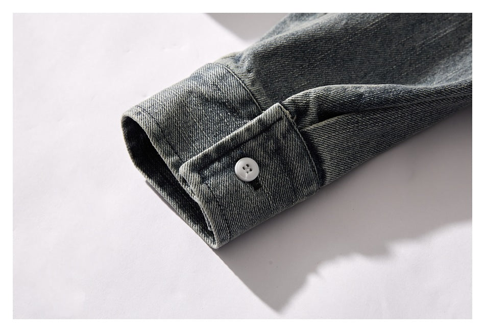 Close-up of a denim jacket cuff with a small white button and stitched tab.