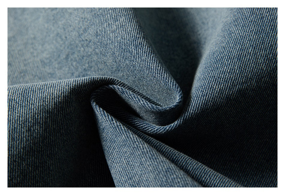 Close-up of blue denim fabric folded to show its diagonal weave and texture.