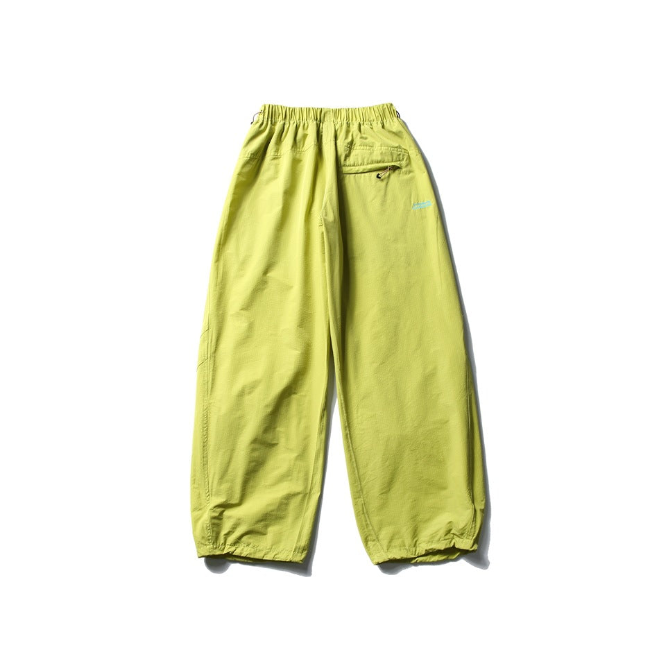 Bright yellow-green wide-leg pants shown from the back, with an elastic waist, zip pocket and adjustable hems.