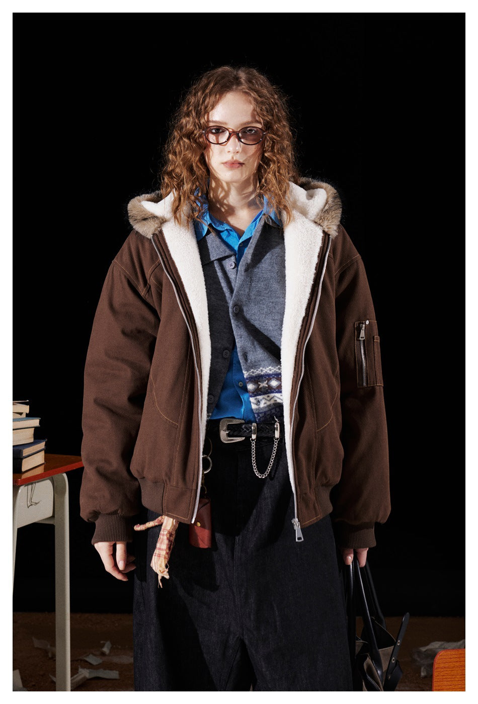 Front view of a model wearing an open brown jacket with cream lining and a tan fur-trimmed hood.