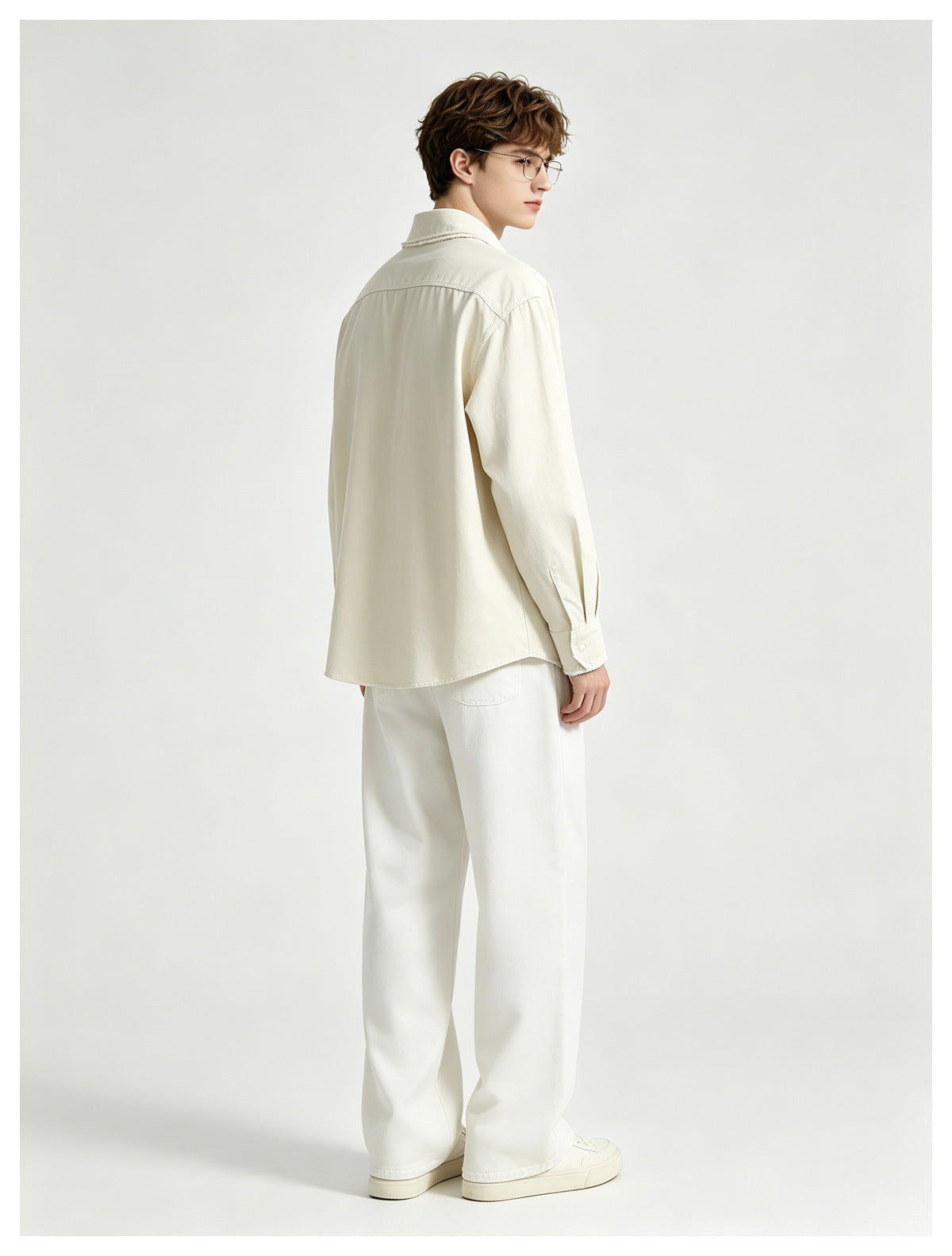 Model wearing an off-white long-sleeve shirt and loose white trousers, shown from behind.