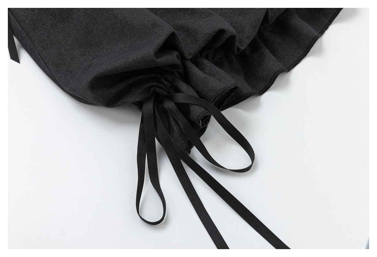 Close-up of gathered skirt fabric with long black ties at the hem.