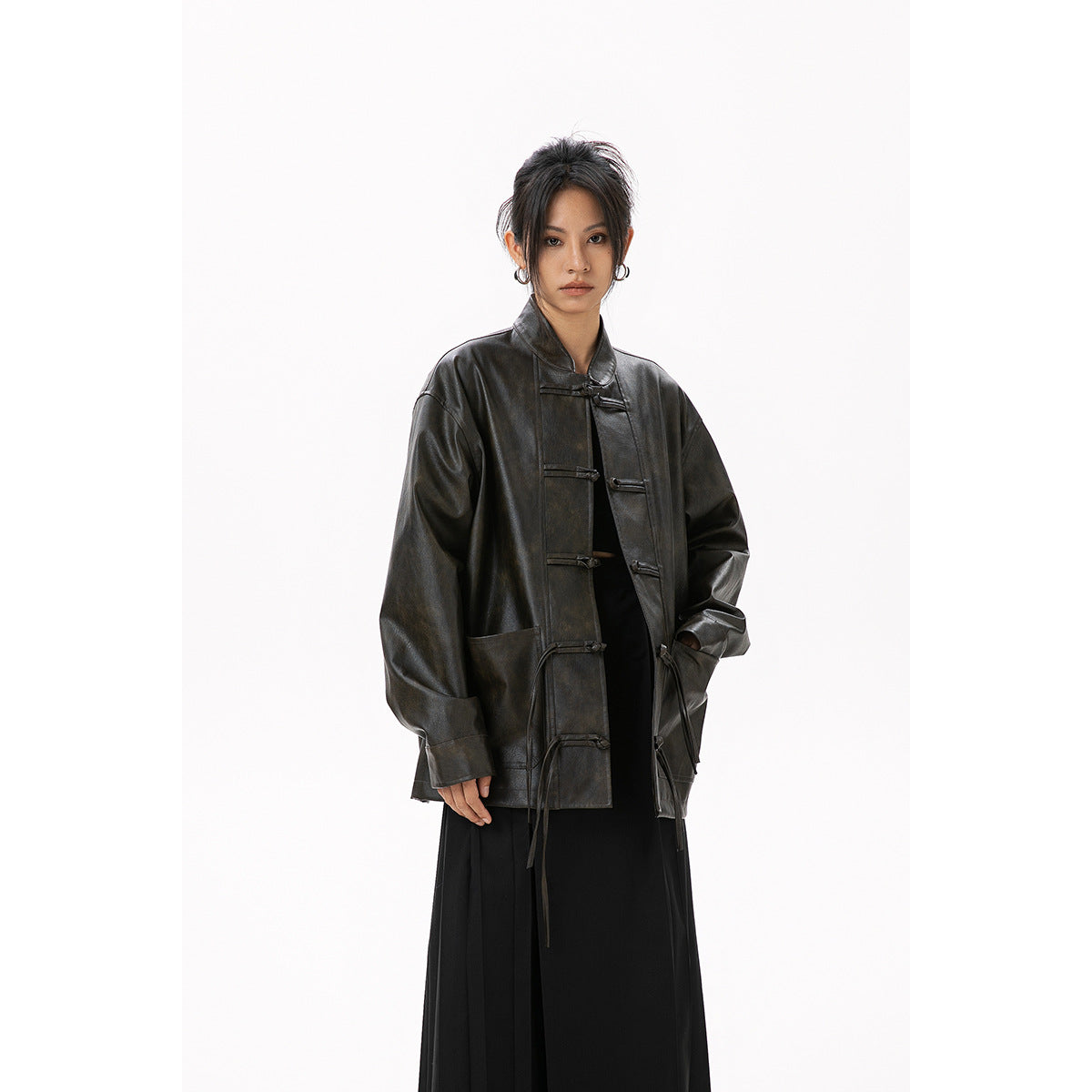 Front view of a model wearing an oversized dark jacket with toggle closures and long ties, paired with a black skirt.