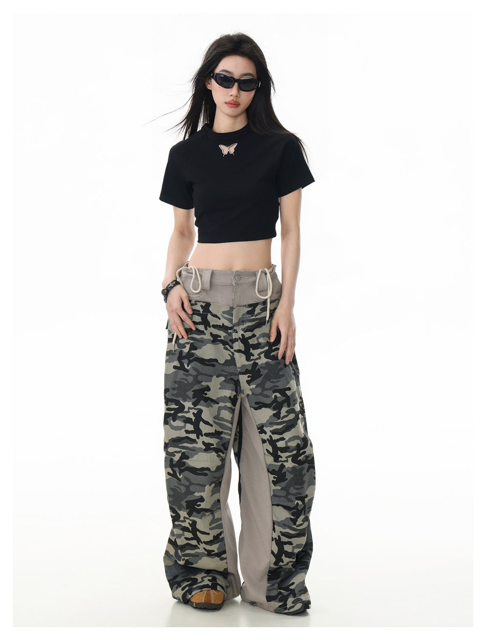 Model in sunglasses wearing a black cropped butterfly T-shirt and loose gray camouflage pants.