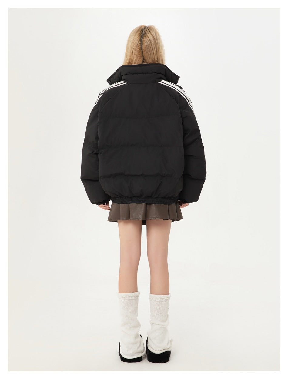 Back view of a model wearing a black quilted jacket with white shoulder stripes and an elastic hem.