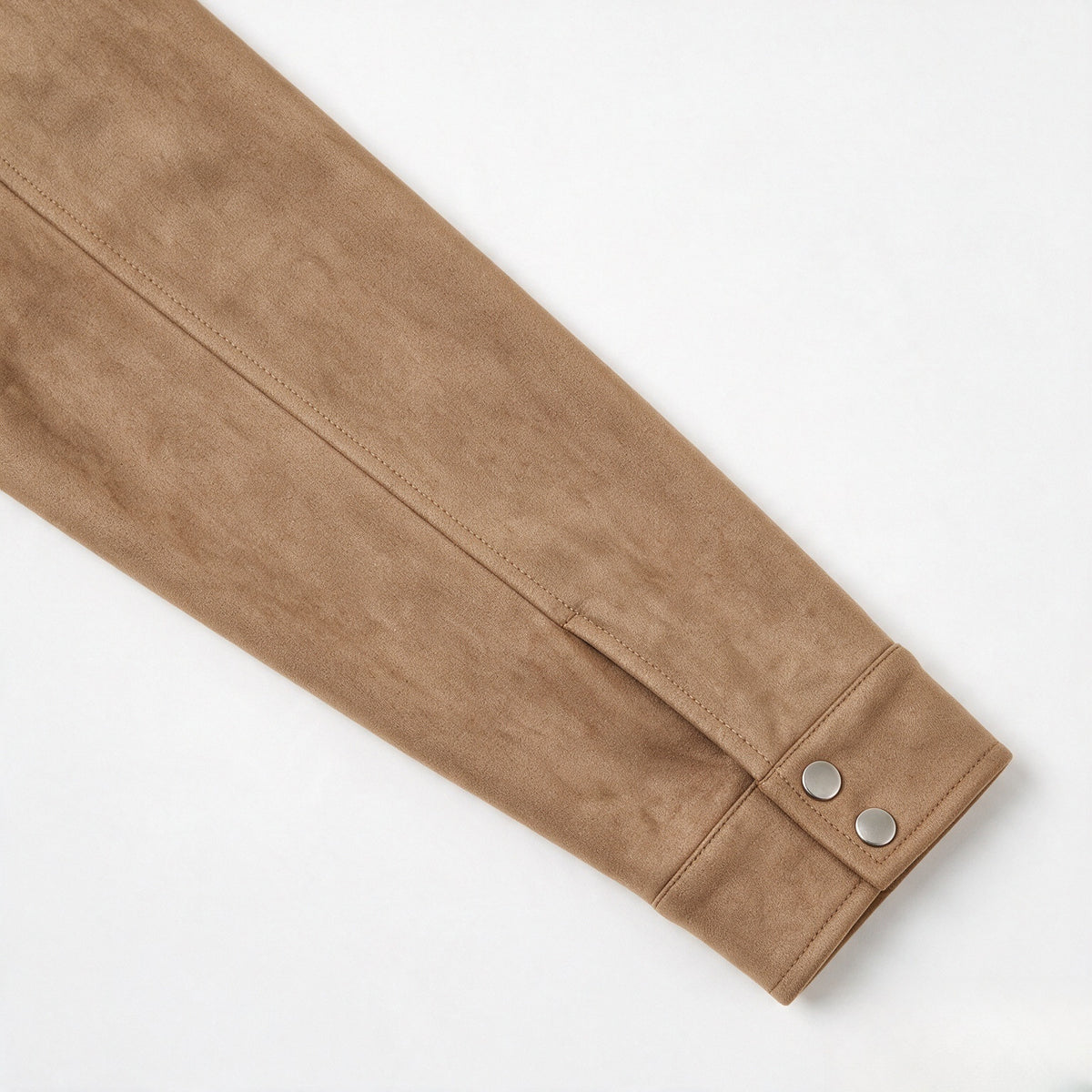 Close-up of a tan jacket sleeve ending in a cuff with two silver snap buttons.