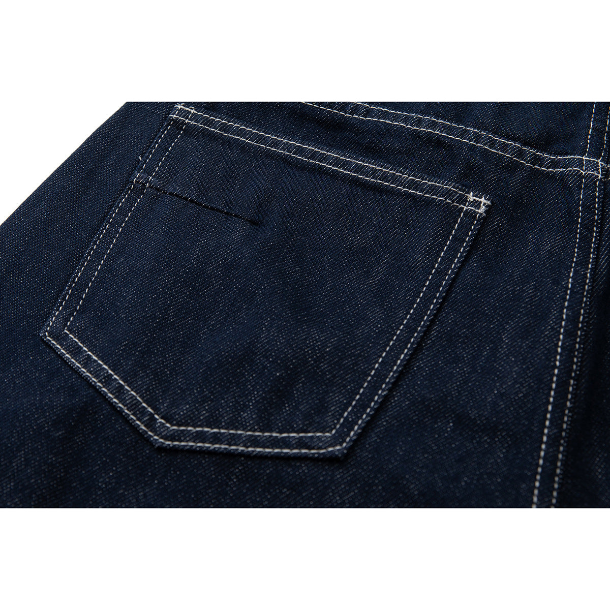 Close-up of a rear patch pocket on dark indigo jeans with contrast stitching.
