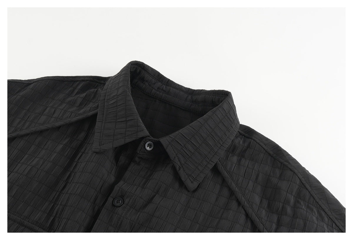 Close-up of a black button-up shirt showing its pointed collar, buttons, and subtle grid texture.