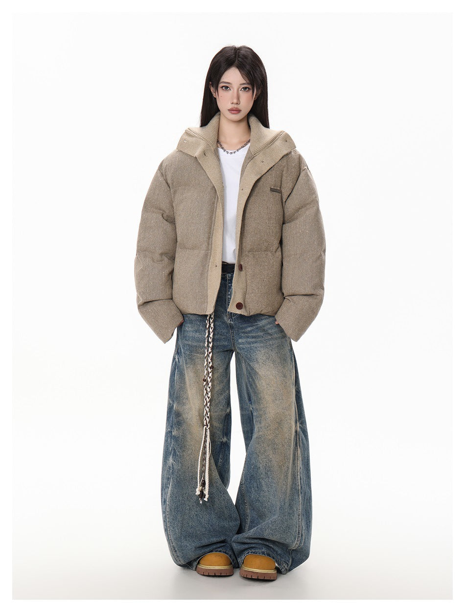 Full-length model wearing a taupe padded jacket with a contrasting wide collar and loose blue jeans.