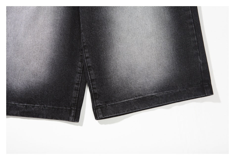 Close-up of the hems of black-gray denim jeans, showing the fading, seams and folded edges.