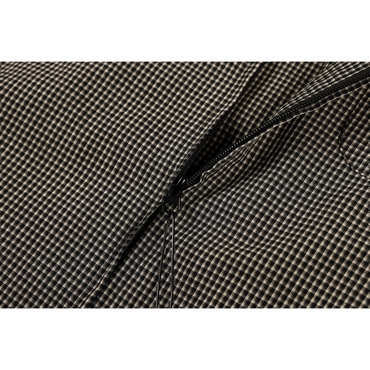 Close-up of a black zipper on black and beige micro-check fabric.