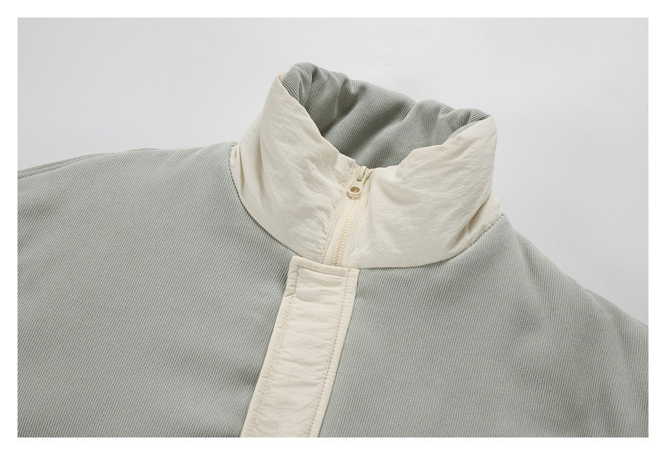 Close-up of a gray jacket with a cream stand collar and cream front zipper placket.
