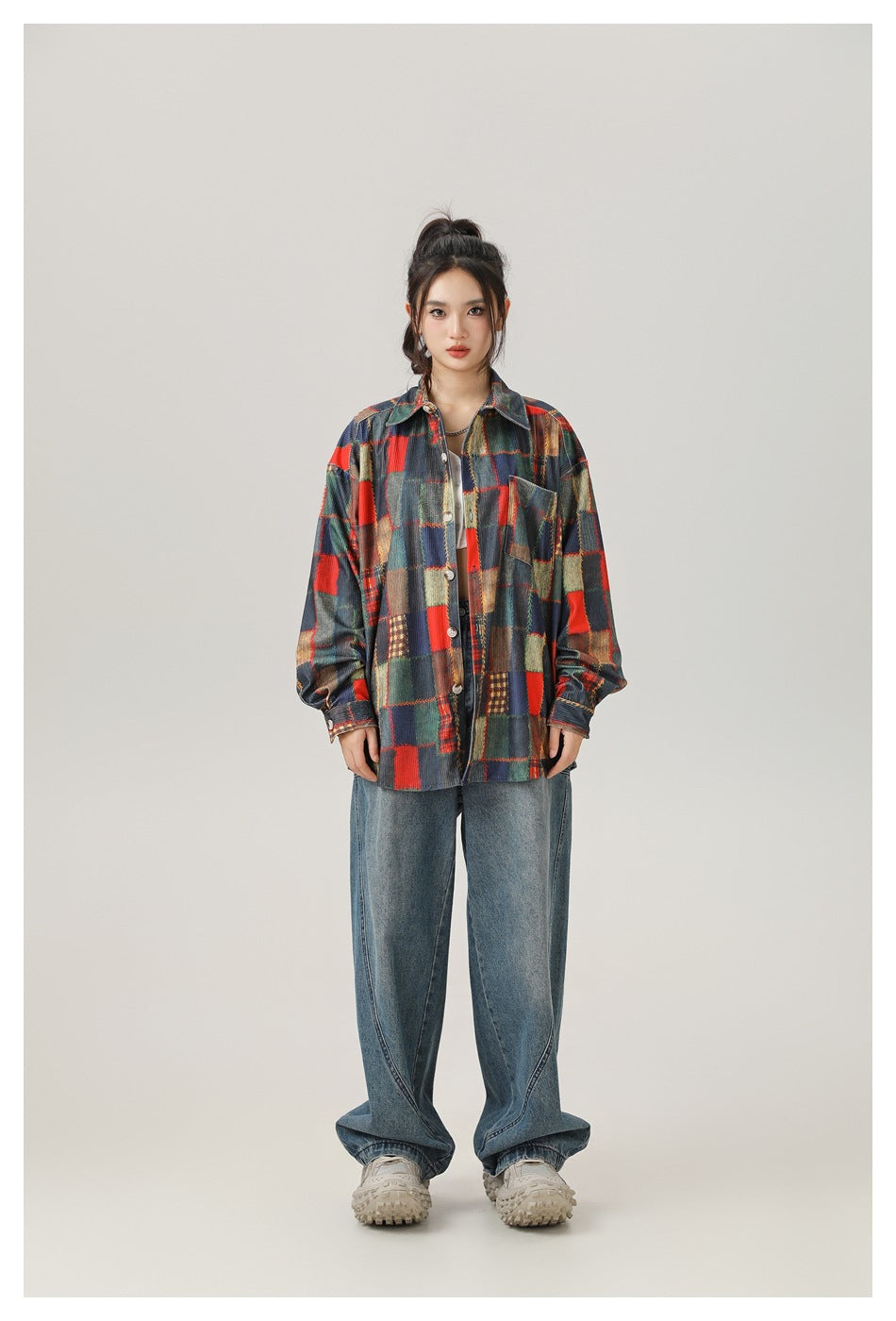 Model wearing an open oversized patchwork print long-sleeve shirt with wide-leg jeans, front view