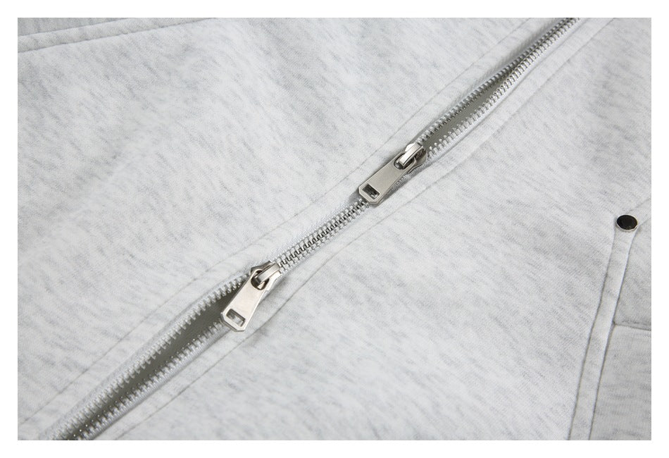 Close-up of the silver two-way zipper and seam details on a light gray marled jacket.