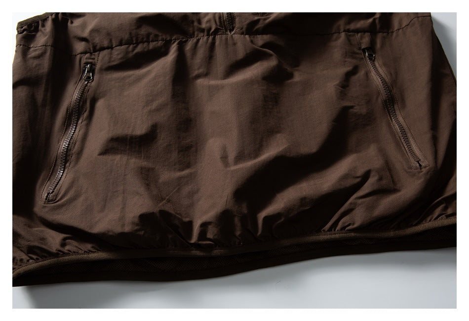 Close-up of the brown vest's lower front, showing two angled zip pockets and the hem.