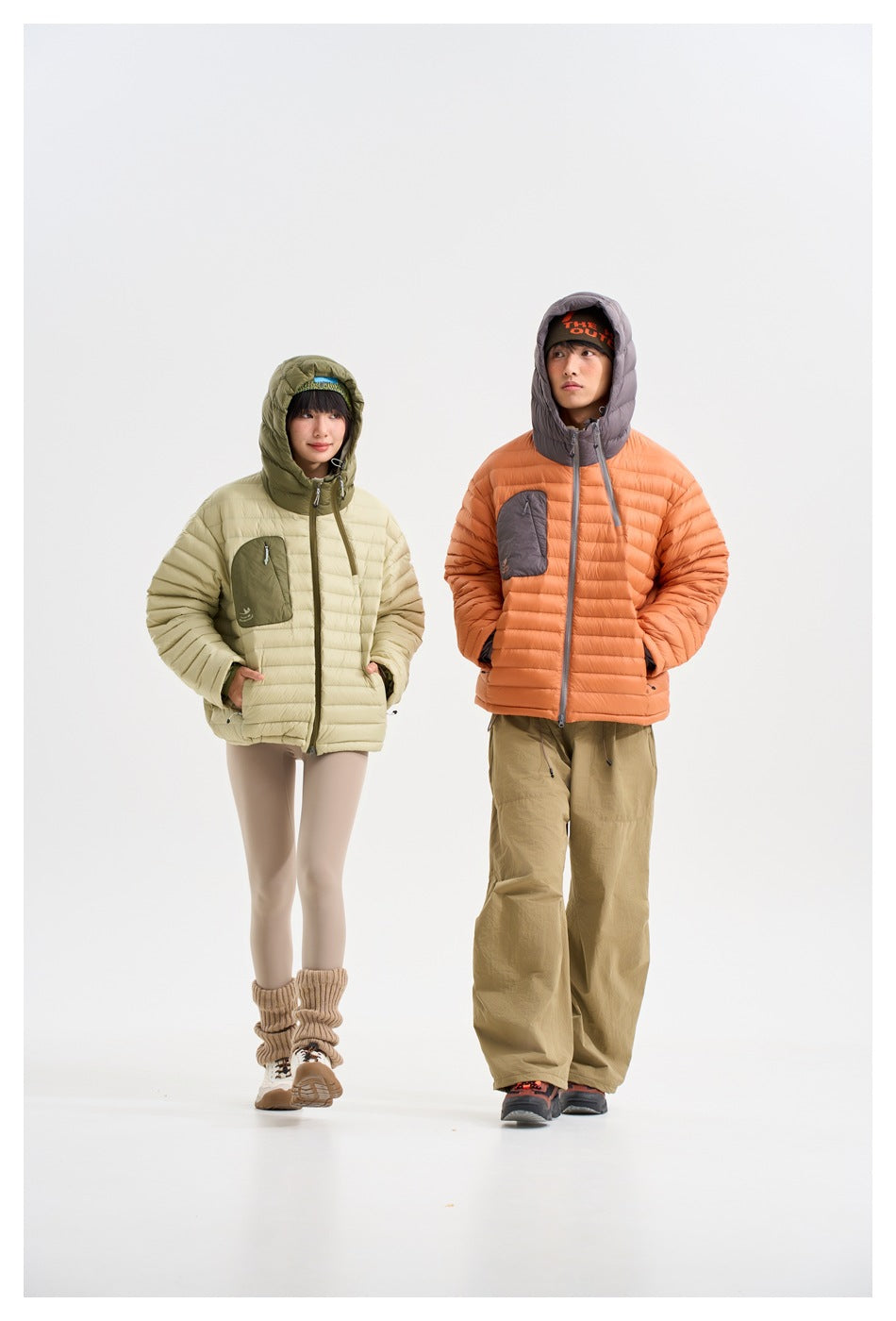 Two models show hooded quilted jackets in pale sage and orange, each with a contrasting chest pocket.