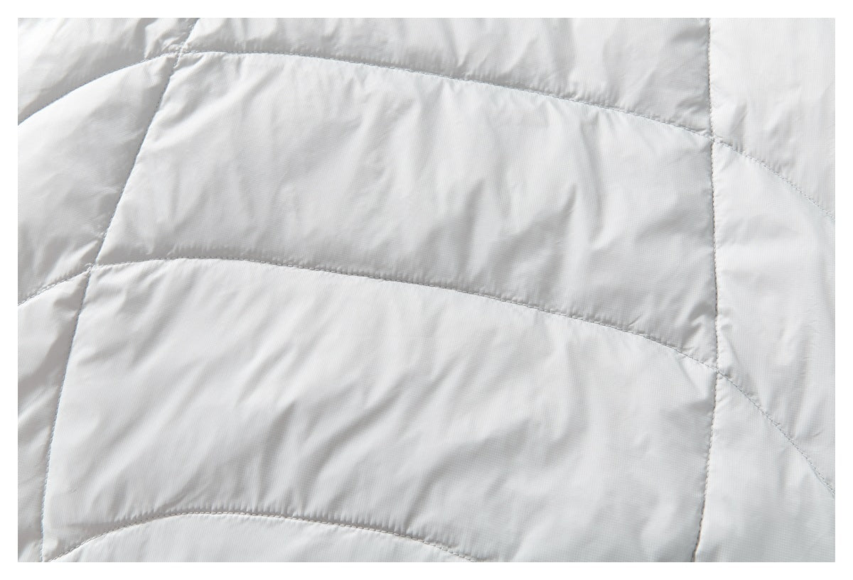 Close-up of white quilted jacket fabric with curved stitched panels.